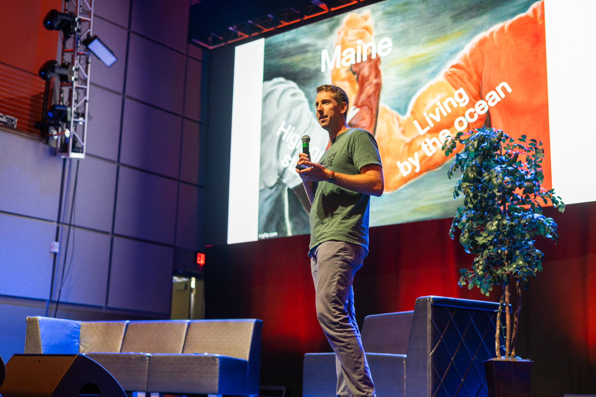 A speaker presenting with a large screen behind them